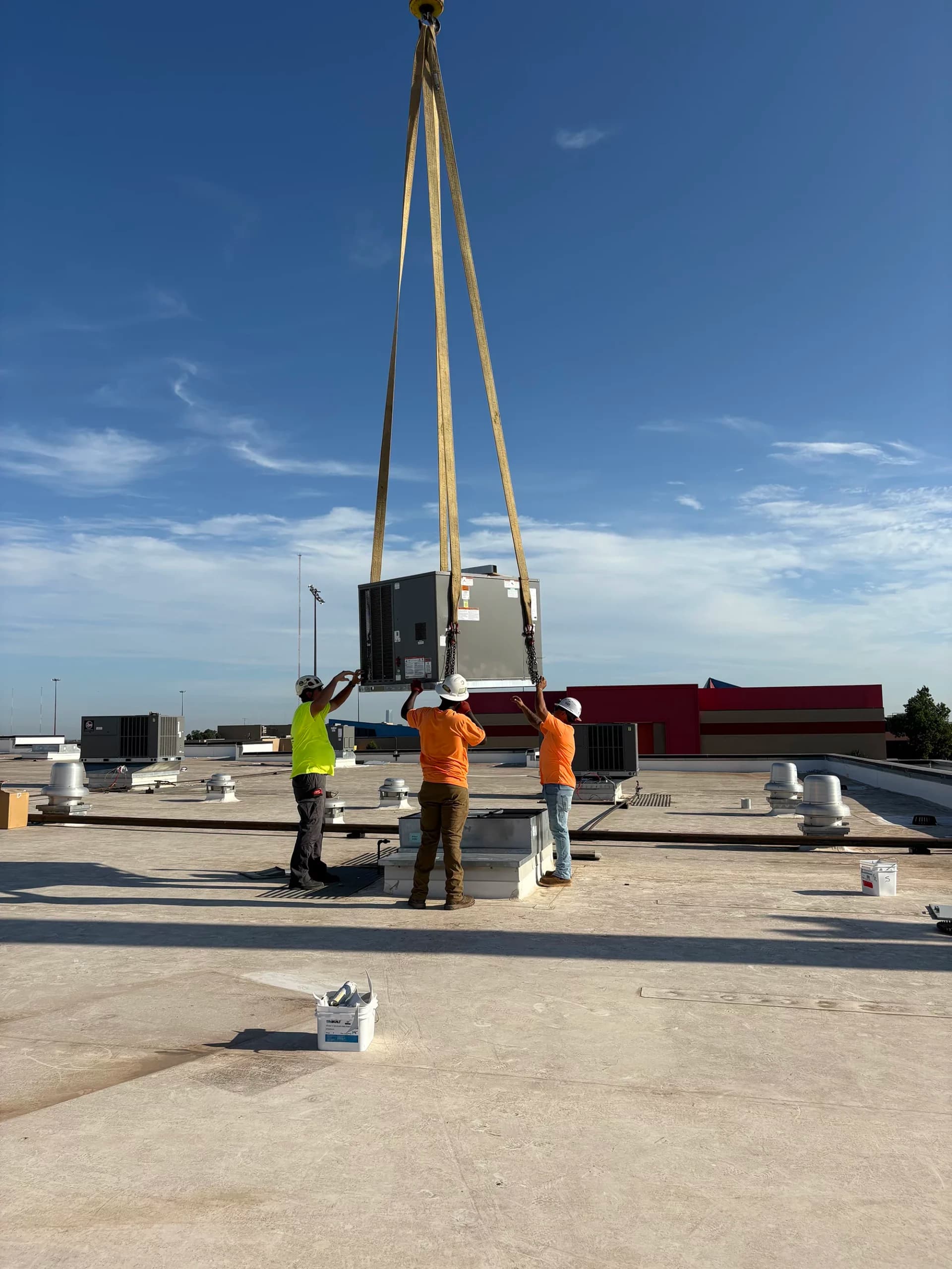Crane lifting a packaged rooftop unit onto a commercial roof