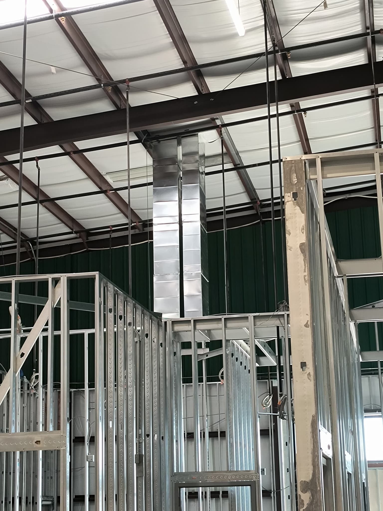 Custom sheet metal duct riser in a metal building under construction