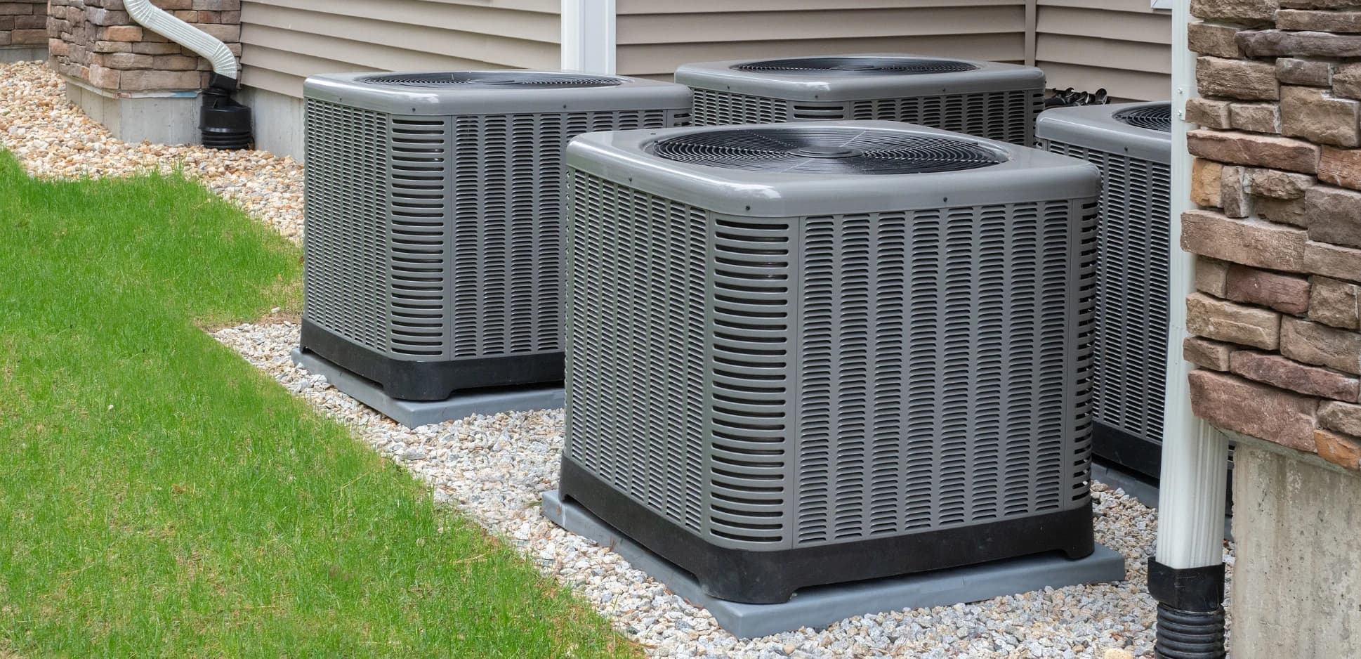 Row of outdoor air conditioning condensers beside a home