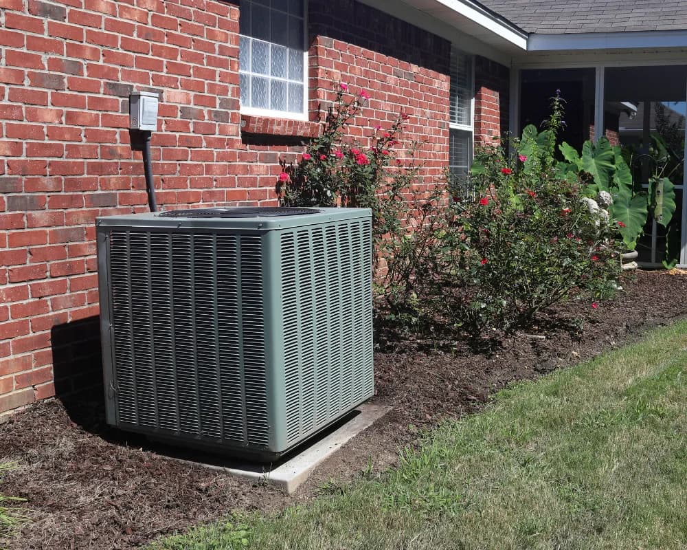 Residential condenser installed beside a brick home