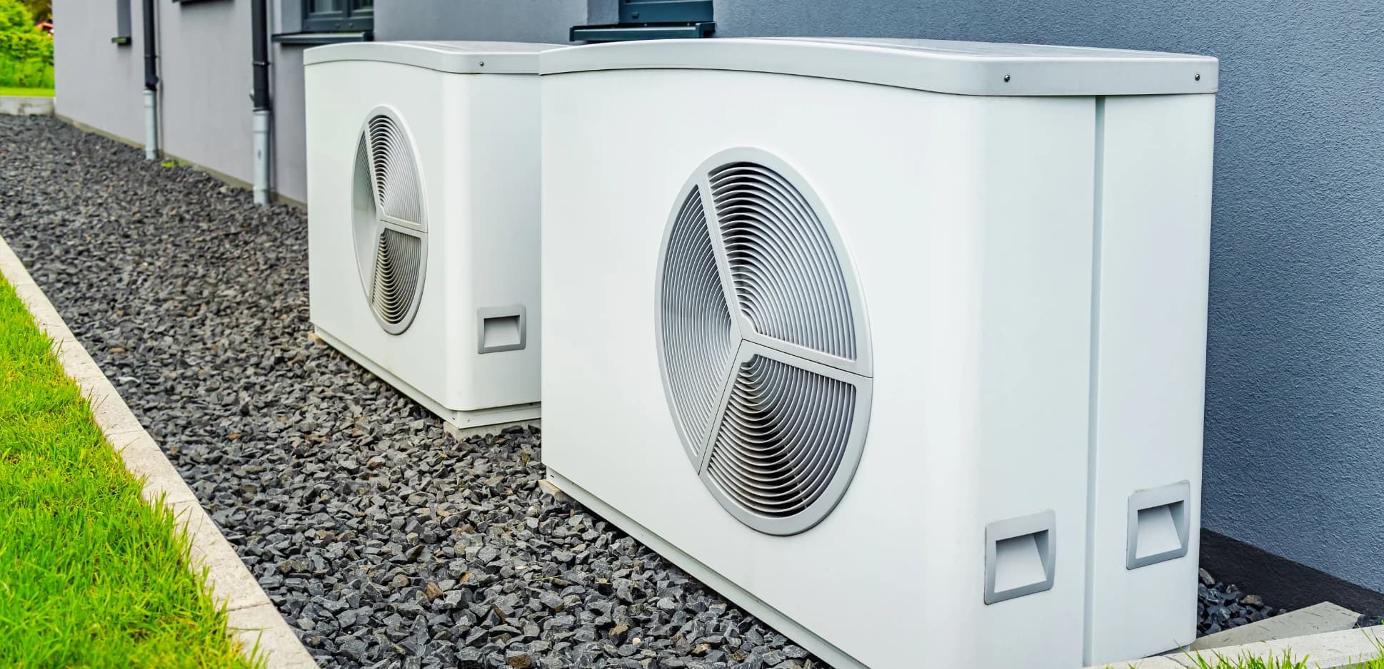 Two outdoor heat pump units installed beside a home