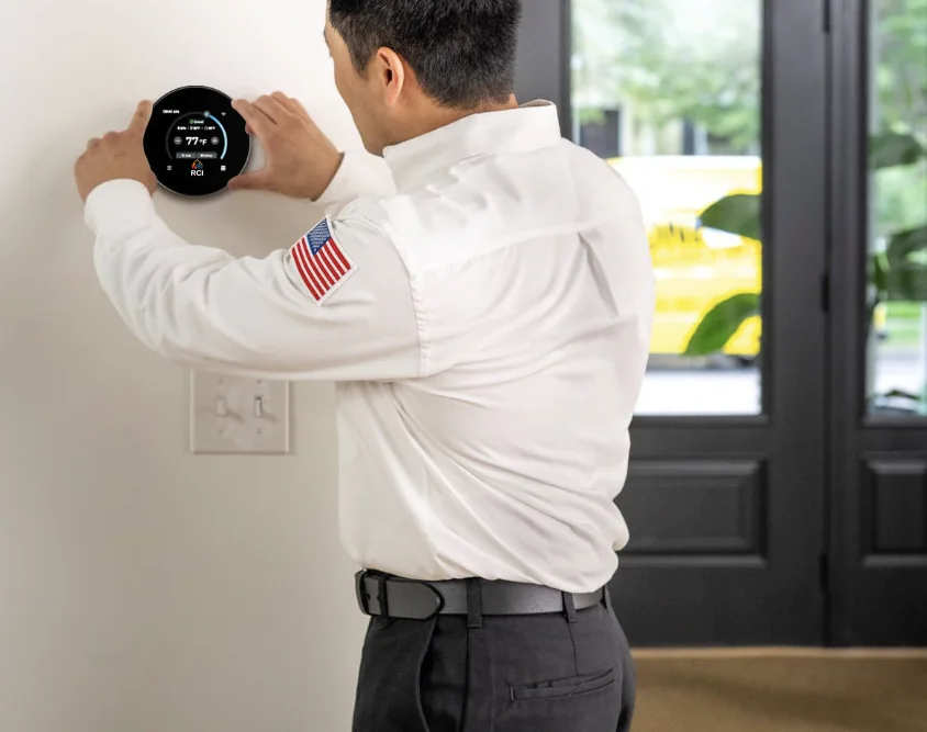 Technician setting an RCI Smart Thermostat on a living-room wall